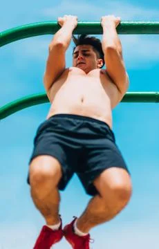 Attractive man pull-ups on a bar against blue sky Stock-Fotos