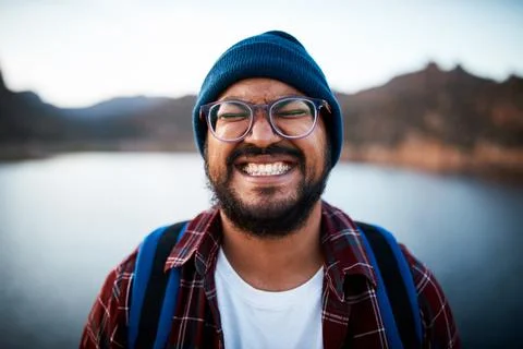 An attractive man pulls a silly grin on a hiking trip by a lake Stock Photos