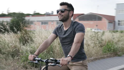 Attractive Man rides his foldable electric bike on the street and smiles Stock Footage 131406347