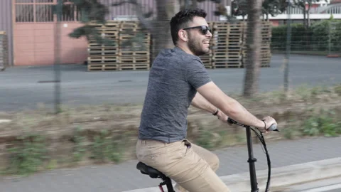 Attractive Man rides his foldable electric bike on the street and smiles Stock Footage 131406532