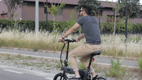 Attractive Man rides his foldable electric bike on the street and smiles Video stock 131407195