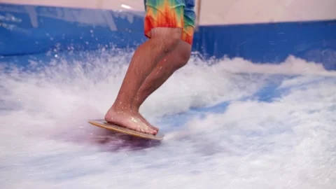 Attractive Man riding surf board on wave simulator indoors. Young surfer during Stock Footage 212362863