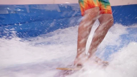 Attractive Man riding surf board on wave simulator indoors. Young surfer during Stock Footage 212363828