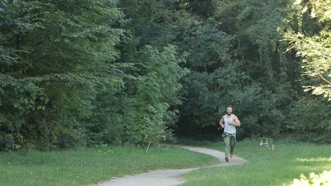 Attractive man running down the walkway in the park .Muscular man running Stock Footage 126496245