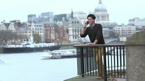 Attractive man talking on his mobile phone on a balcony in the middle of a city Video stock 12719498