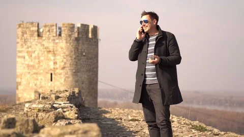 An attractive man talking on a phone in front of a fortress in Belgrade Stock Footage 102823328