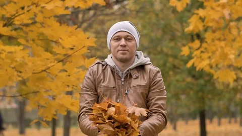 Attractive man throws up maple leaves in autumn in the park. Emotions, good mood Stock Footage 120191644