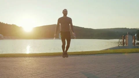 Attractive man training on skipping rope on outdoor workout near lake sportsman Stock Footage 138649695