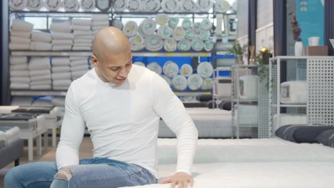 Attractive man trying new bed at furniture store Stock Footage 148346947