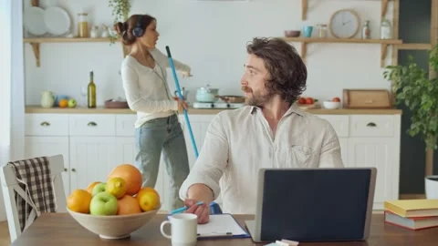Attractive Man Trying to Work Remotely While His Wife With Headphones Dancing Stock Footage 140335990