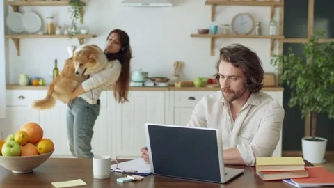 Attractive Man Trying to Work Remotely While His Wife With Headphones Holding in Video stock 140414615