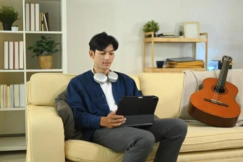 Attractive man using digital tablet relaxing on couch at home Foto stock