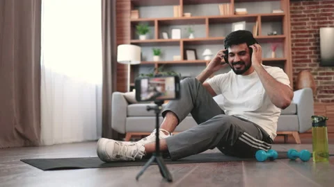 Attractive man using headphones while working out at home Stock Footage 236529683