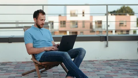 Attractive man using laptop outside outdoors on roof family time online designer Stock Footage 114291248