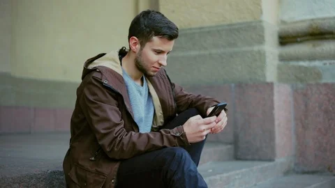 Attractive man using phone sitting on the steps in an office building. Stock Footage 97156604