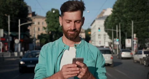 Attractive man walking between driving Cars on the Road with Mobile Phone. Stock Footage 122990545