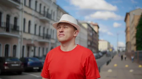 Attractive man in a white hat walks along the city street, examines everything Stock Footage 137290973