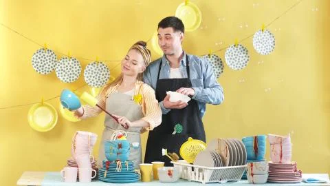 Attractive married couple using a brush and sponge wash dirty dishes, plates Stock Photos