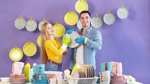 Attractive married couple using a brush and sponge wash dirty dishes, plates Stock Photos