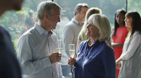 Attractive mature couple chatting and flirting together at a social gathering. Stock Footage