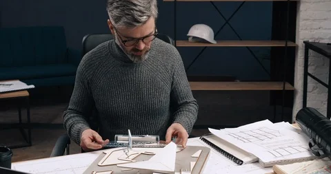 Attractive Middle aged Architect measuring Wooden model of Airport Building Stock Footage 126246148