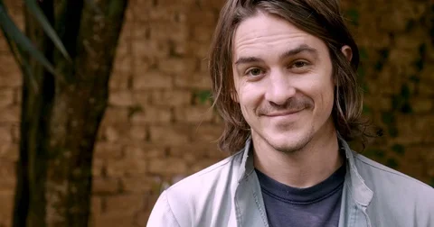 Attractive millennial man in his 20s or 30s looking at the camera and smiling Video stock 80809527
