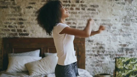 Attractive mixed race young joyful woman have fun dancing near bed at home Stock Footage