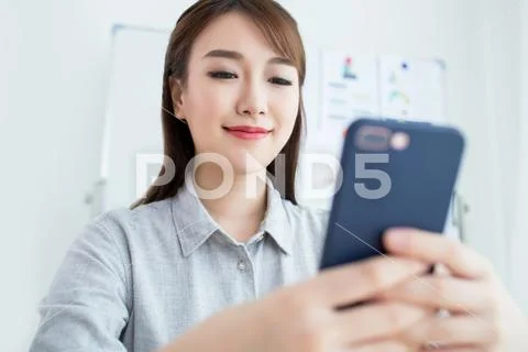 Attractive office worker sitting at desk and useing her phone Stock Photos