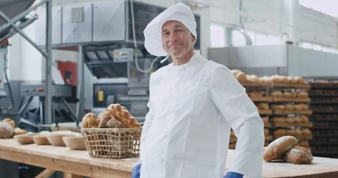 Attractive old baker man portrait smiling large in a bakery industry he crossed 스톡 동영상 112140201
