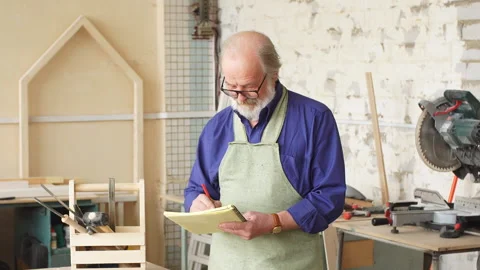 Attractive old carpenter working on designs in his workshop. Stock Footage 89714748