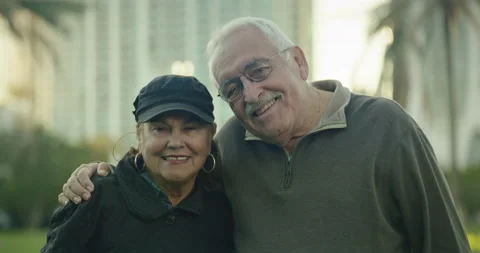 Attractive older couple looking at camera and smiling at a park Stock Footage 234530800