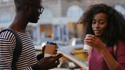 Attractive optimistic African couple drinking coffee in date on busy street of Stock Footage 81838750