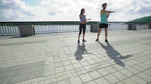 Attractive people working out on the bridge, warm-up and stretching of the arms Stock Footage 65372814