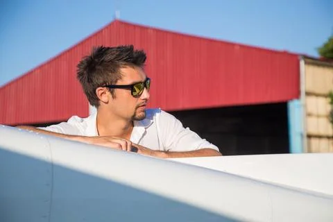 Attractive pilot standing in front of plane Stock Photos