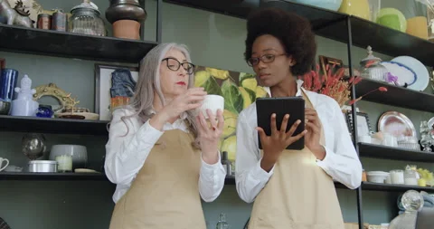 Attractive positive friendly elderly female owner of gift shop explaining to her Stock Footage 143980739