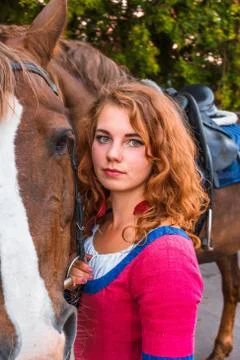 Attractive pretty red-haired young girl looks at the camera, clinging to the hor Stock Photos