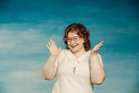 Attractive red-haired plump woman in a white suit adjusts red glasses on a bl Stock Photos