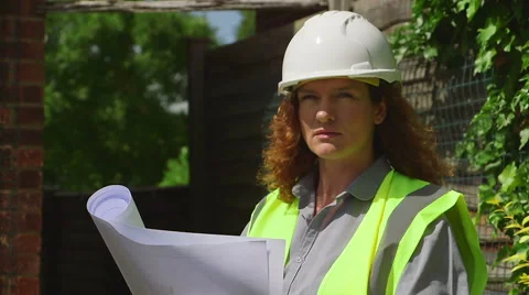 Attractive red-headed female architect / engineer looks at plans then smiles Stock Footage 52300431