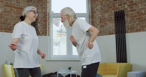 Attractive satisfied funny 70-aged couple in white t-shirts and sports pants Stock Footage 146520816