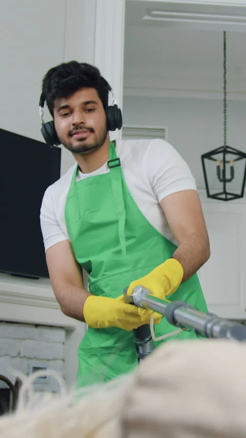 Attractive satisfied responsible 30-aged bearded cleaner cleaning sofa with vacu Stock Footage 327869636