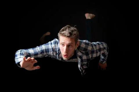 Attractive scared male fall down from height on dark background Stock Photos