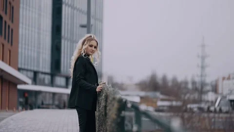Attractive, seductive blonde, looks over the bridge seriously, displays a Stock Footage 157449423
