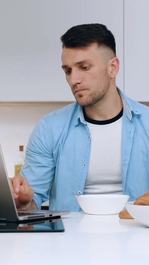 Attractive serious 35-aged guy enjoying fresh milk and attantivly watch on lapto Stock Footage 334726573