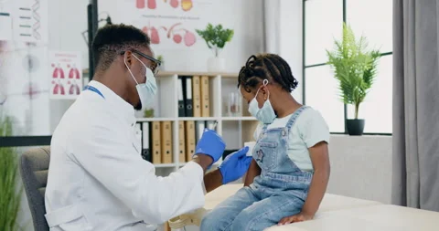 Attractive skillful professional black-skinned male doctor in facial mask doing Stock Footage 156259503