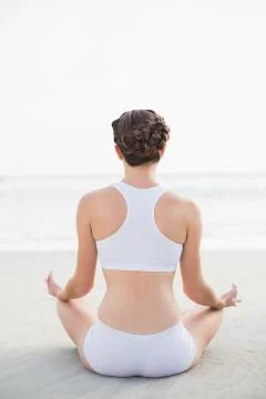Attractive slim brown haired model in white sportswear meditating in lotus Stock Photos