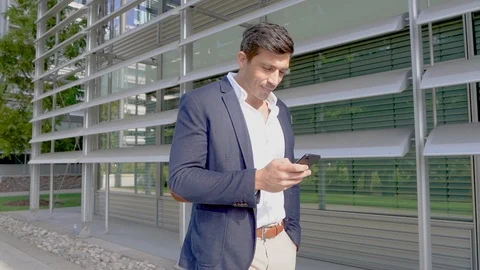 Attractive smart man using phone and smiling, slow motion Stock Footage 96049211
