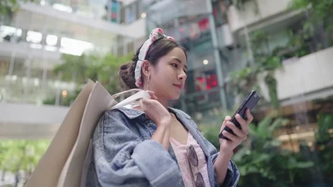 Attractive Smiling asian customer using phone inside modern mall Stock Footage 196895317