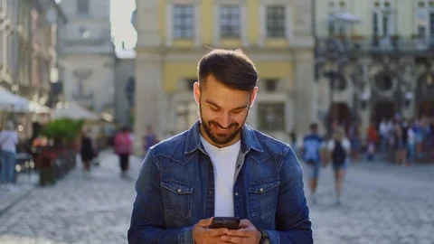 Attractive smiling bearded young guy in jeans jacket writing massage in the midd Stock Footage 112355214