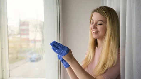 Attractive smiling blonde girl washes Windows pre-applied spray, house cleani Stock Footage