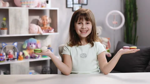 Attractive smiling cute school kid girl holds four tasty cookies in her hands Stock Footage 194813571